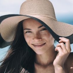 A woman hiding herself from the sun with a sun hat